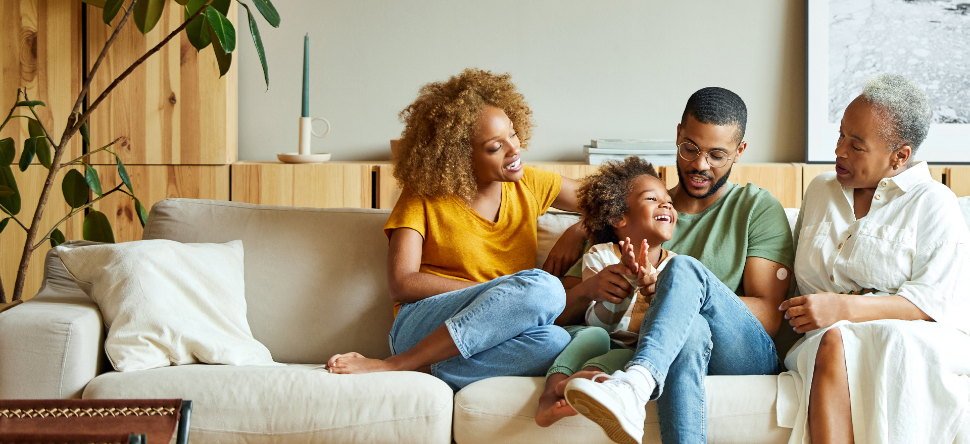 Woman with a continuous glucose monitor sits on couch with her family