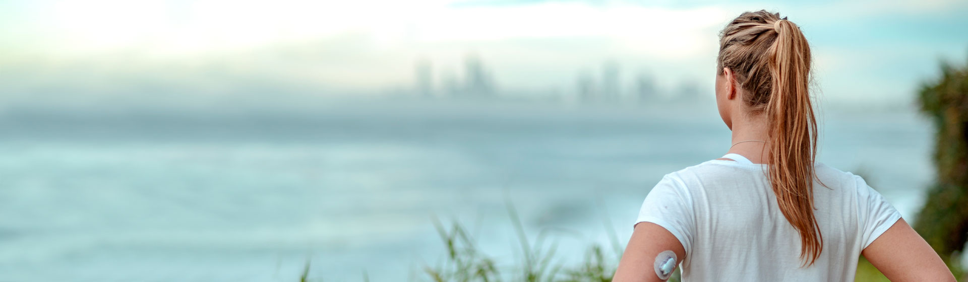 Young girl with diabetes device looking at the ocean