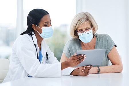 Doctor using tablet during consultation with senior woman