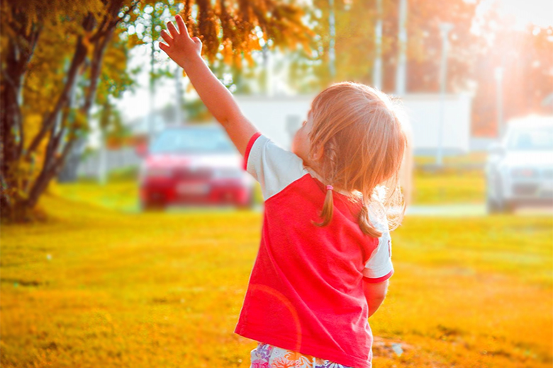 Little girl reaching for a tree