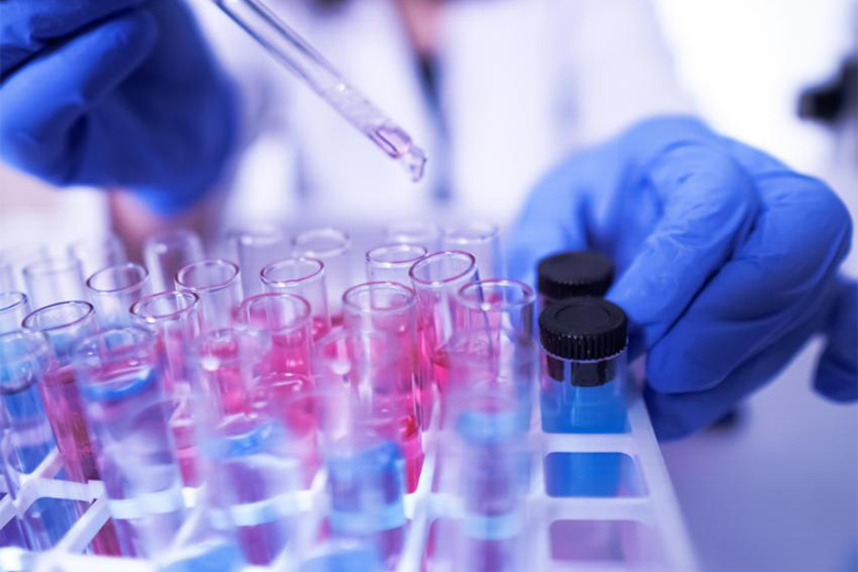 Researcher using a dropper over test tubes