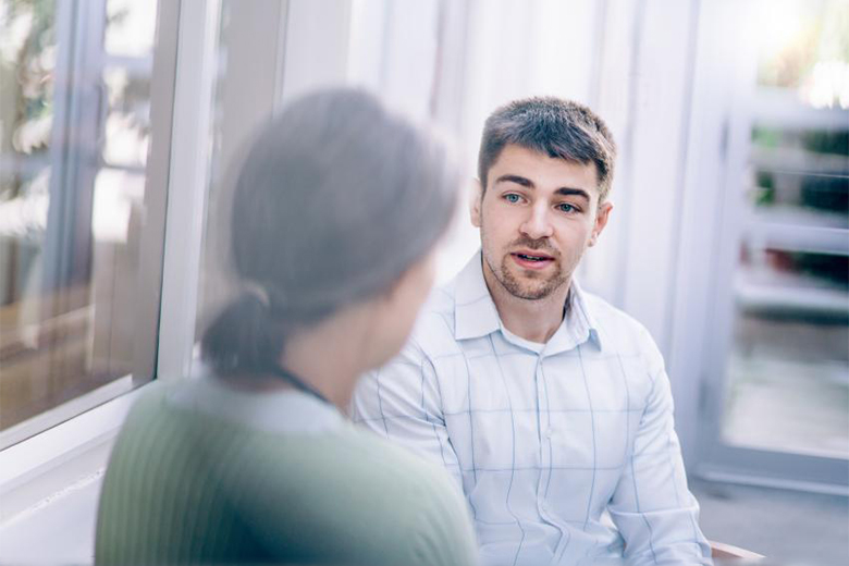 Younger adult male talking to an elderly woman